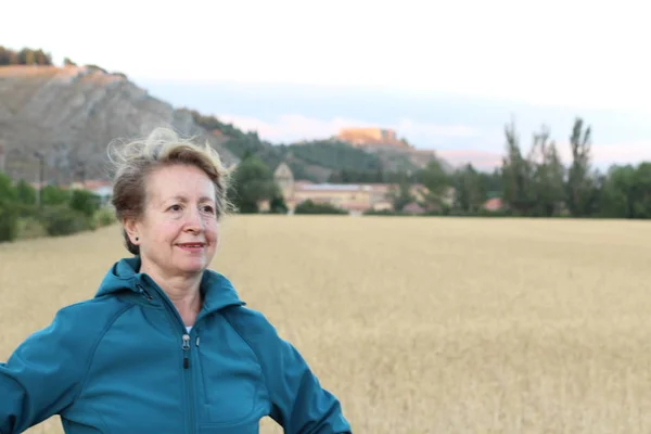 Free woman enjoying nature sunset. Freedom and serenity concept with mature natural female model. Caucasian female model in her 60s enjoying sunset from a wheat field