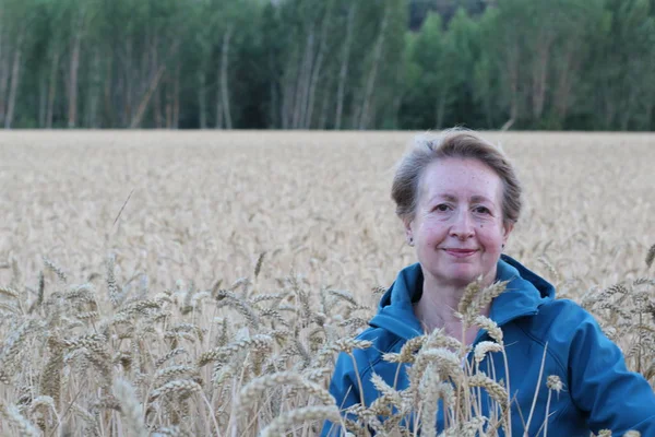 Free woman enjoying nature sunset. Freedom and serenity concept with mature natural female model. Caucasian female model in her 60s enjoying sunset from a wheat field