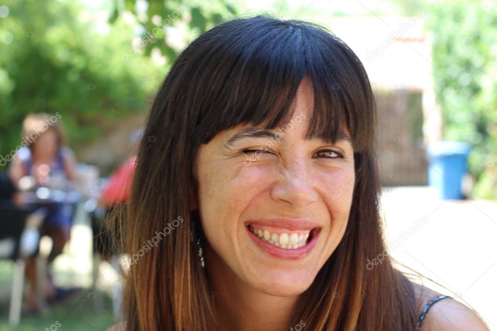 Portrait of beauty brunette woman sitting in cafe at summer park, blurred background  