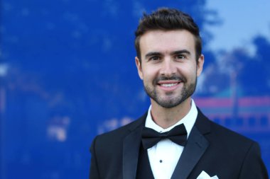 Takım elbiseli göz kamaştırıcı adam şehir geçmişinde duruyor. 