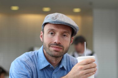 Closeup of handsome man with hipster look drinking coffee in cafe