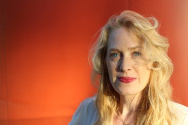 Turuncu arka planda duran olgun kadın portresi. 