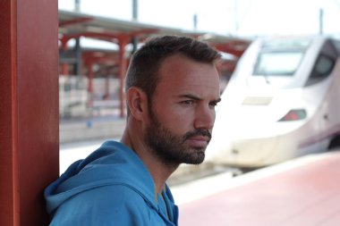 Tren istasyonunda bekleyen yakışıklı sakallı adam.