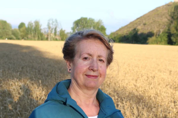 Free woman enjoying nature sunset. Freedom and serenity concept with mature natural female model. Caucasian female model in her 60s enjoying sunset from a wheat field