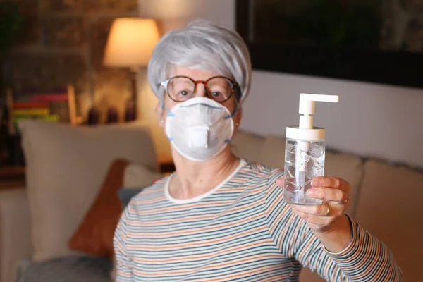 Sick senior woman using hand sanitizer at home