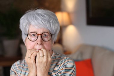Horrified senior woman at home clipart