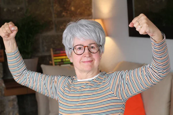 Strong senior woman showing biceps