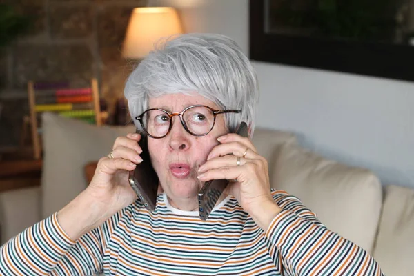 Стресс Пожилая Женщина Помощью Двух Телефонов Одновременно — стоковое фото