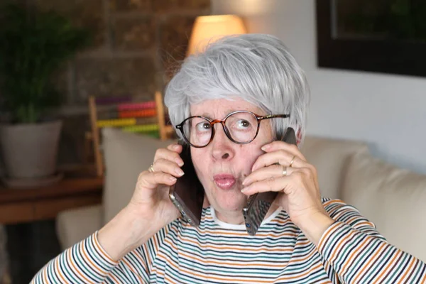 Stres Starší Žena Pomocí Dvou Telefonů Současně — Stock fotografie