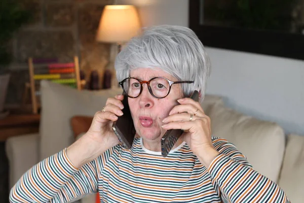 Стресс Пожилая Женщина Помощью Двух Телефонов Одновременно — стоковое фото