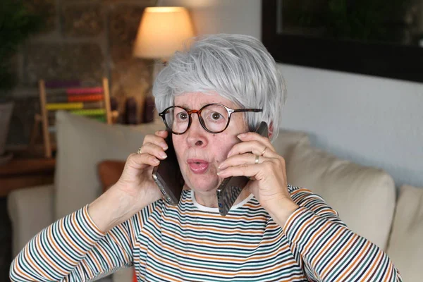 Mulher Idosa Estressada Usando Dois Telefones Simultaneamente — Fotografia de Stock