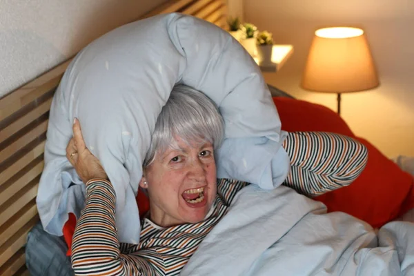 Ώριμη Γκρίζα Μαλλιά Γυναίκα Που Καλύπτει Αυτιά Μαξιλάρι Ενώ Βρίσκεται — Φωτογραφία Αρχείου