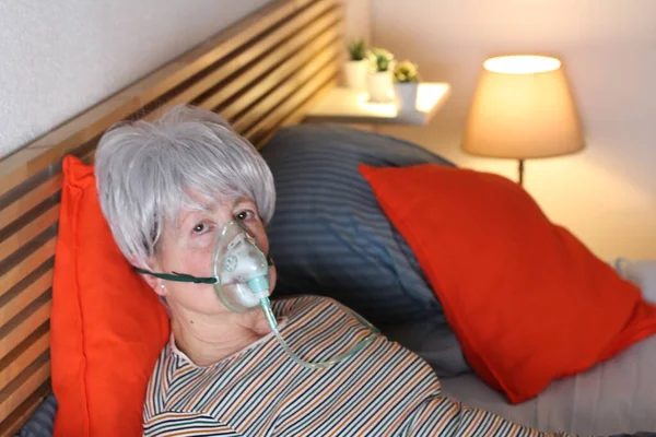 Ώριμη Γκρίζα Μαλλιά Γυναίκα Μάσκα Οξυγόνου Ενώ Χαλαρώνοντας Στο Κρεβάτι — Φωτογραφία Αρχείου