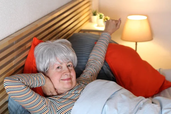 Ώριμη Γκρίζα Μαλλιά Γυναίκα Που Τεντώνεται Ενώ Χαλαρώνει Στο Κρεβάτι — Φωτογραφία Αρχείου
