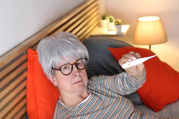 Dojrzała Siwowłosy Kobieta Pokazując Termometr Podczas Relaksu Łóżku Podczas Samodzielnej — Zdjęcie stockowe