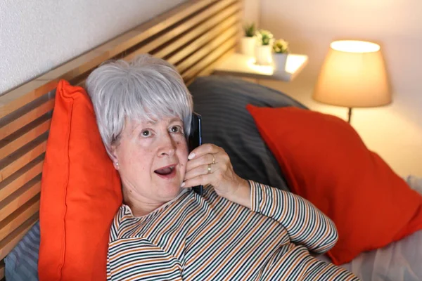 Zralé Šedovlasá Žena Telefonicky Při Relaxaci Posteli Během Vlastní Izolace — Stock fotografie