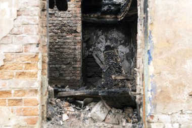 Doorway of a burnt brick house, charred boards after a fire.
