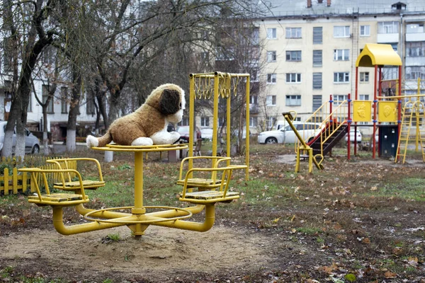 Bulutlu havada Rus bahçesinde metal salıncakta sallanan büyük, yumuşak bir oyuncak köpek..