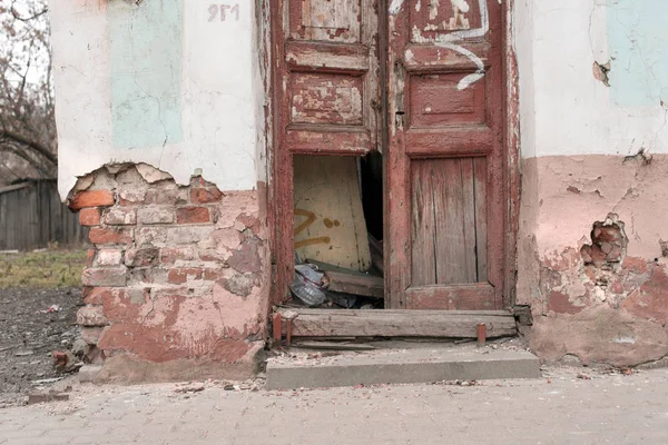 Wooden door and brick wall of a crumbling old house, closeup.