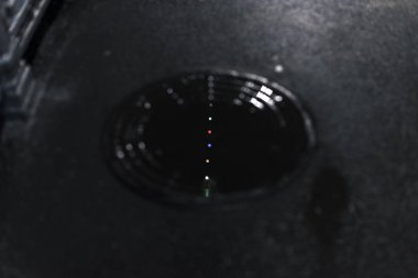 Reflection of multi-colored lights in a puddle on the sewer manhole in the city at night.