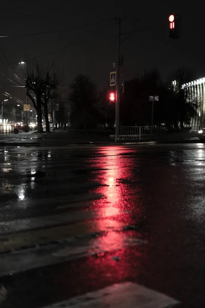 Reflection of traffic lights in puddles on the street of a night city.