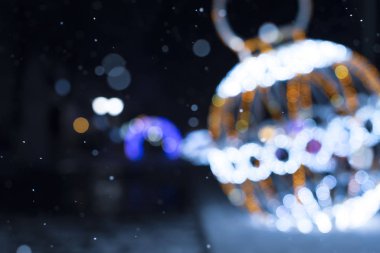 Bulanık festival arka planı, düşen kar ve Noel ve yeni yıl sokak dekorasyonu, parlak ışıklar ve büyük bir Noel balosu..