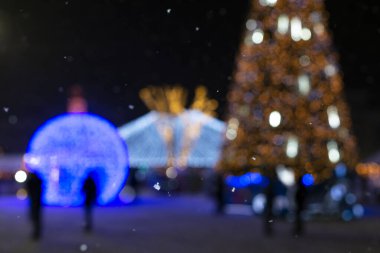 Yılbaşı ve yeni yıl ışıklarının arka planında yağan kar taneleri, bulanık arka plan ve güzel bokeh.