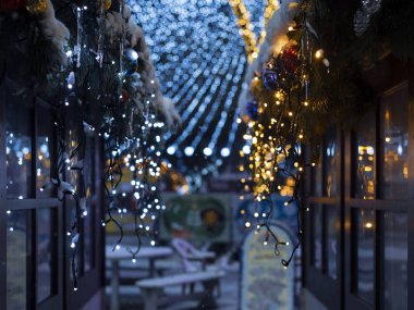 Noel ve Yeni Yıl evlerinden sarkan fenerlerle süslü çelenkler ladin dalları ve bulanık bir arka plan ve güzel bir bokeh ile Noel baloları..