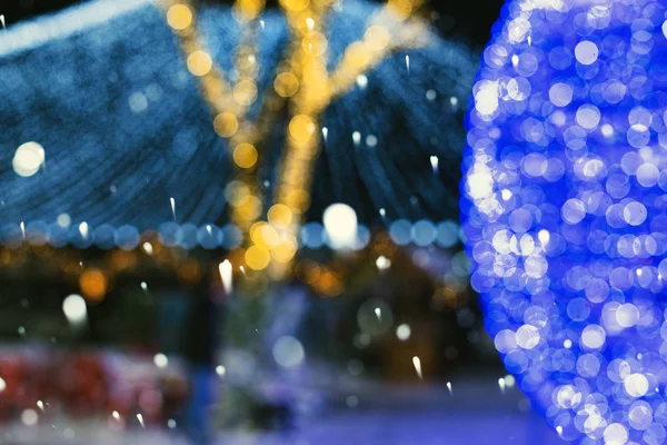 クリスマスと新年の街の明かりを背景に雪の結晶が落ち 背景がぼやけて美しいボケ — ストック写真