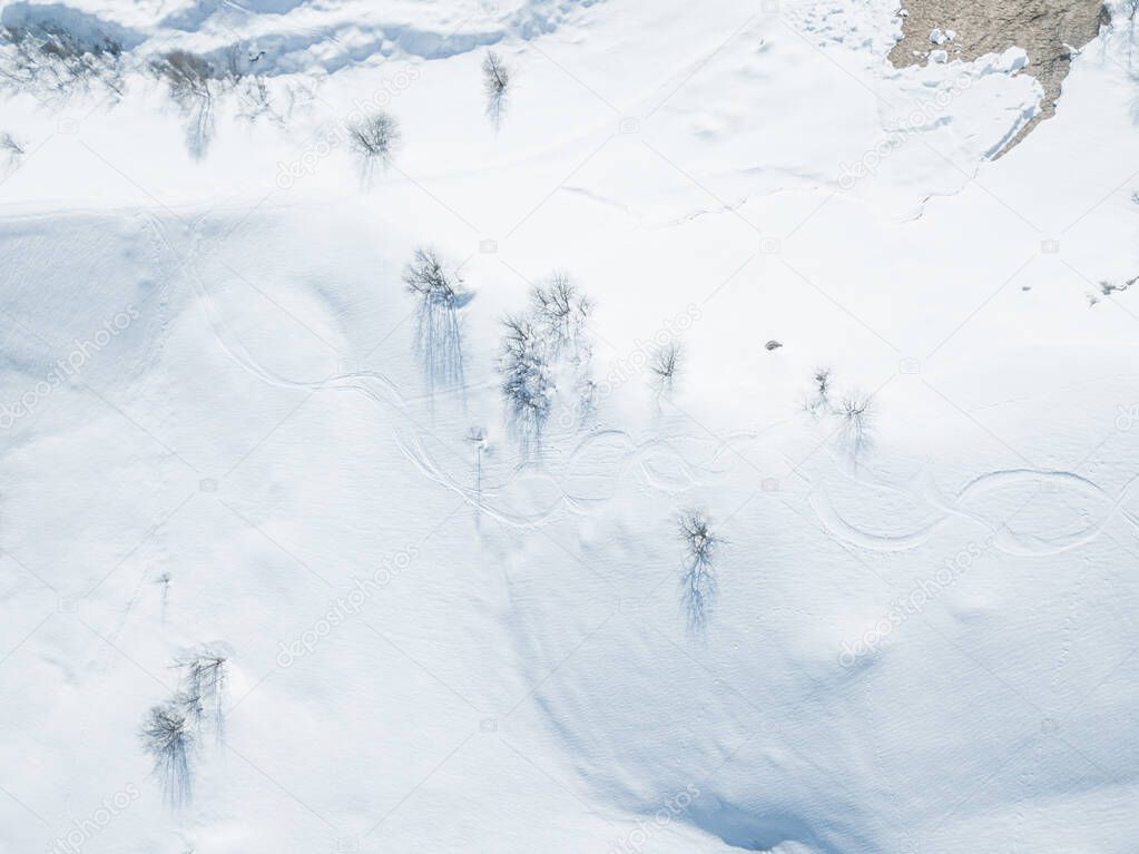 Aerial view of ski tracks in snow. Backcountry skiing in powder, leaving trails in snow.