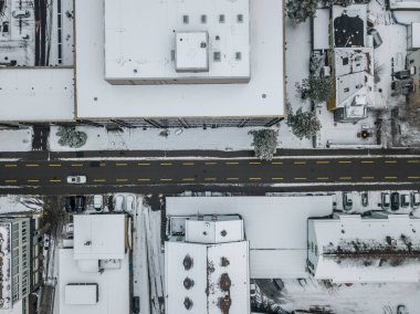 Karla kaplı çatıları olan İsviçre şehrindeki hava manzaralı yol