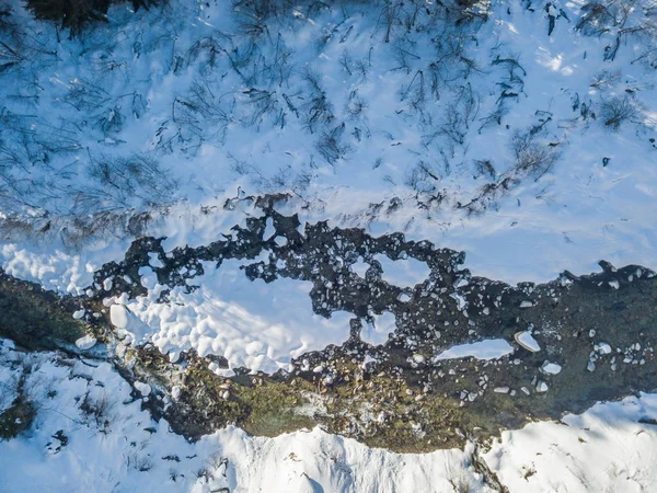 空中俯瞰流过冬季的河流中覆盖着积雪的石头 — 图库照片