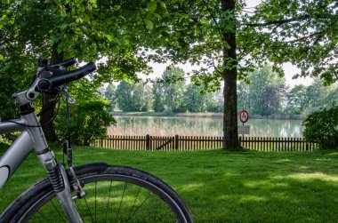 Romantik gölün önünde, yemyeşil ağaçların arasında bisiklet sürmek.