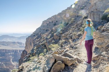 Jebel Shams Kanyonu boyunca yürüyen bir kız.