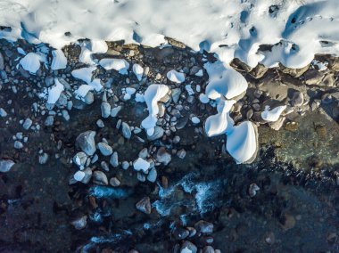 Nehirde kış boyunca akan karla kaplı taşların havadan görünüşü