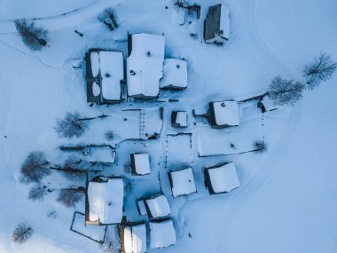 İsviçre'de küçük kırsal kasabada karla kaplı evlerin havadan görünümü