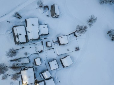 İsviçre'de küçük kırsal kasabada karla kaplı evlerin havadan görünümü