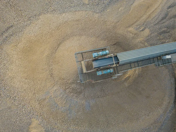 Aerial view of conveyor belt above sand cone in open pit quarry. Industrial mining for gravel in Switzerland.