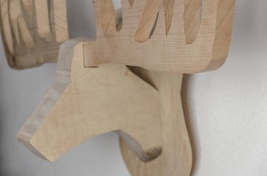 Beyaz duvarda asılı duran ahşap boynuz kupası, soyut hayvan heykeli.