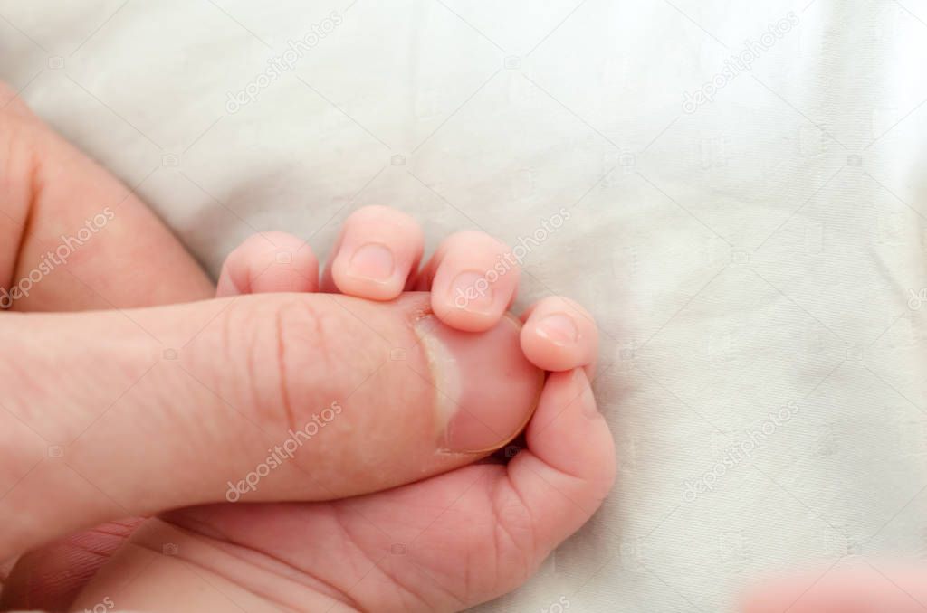 Hand of newborn baby holding male adult's finger. Concept of help and family. Father holding hand.