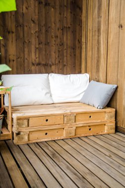 Balkonda rahat ahşap bir kanepe.