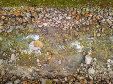 Suda taşlar ve kayalar olan sakin deniz yüzeyinin havadan görünüşü.