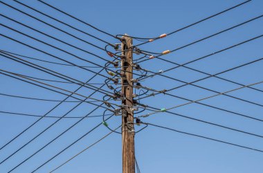 Wooden power pylon with many cables in four directions in Oman