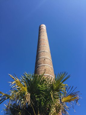 Mavi gökyüzünün önündeki eski kırmızı tuğla baca