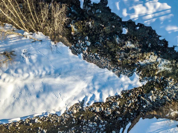 空中俯瞰流过冬季的河流中覆盖着积雪的石头 — 图库照片