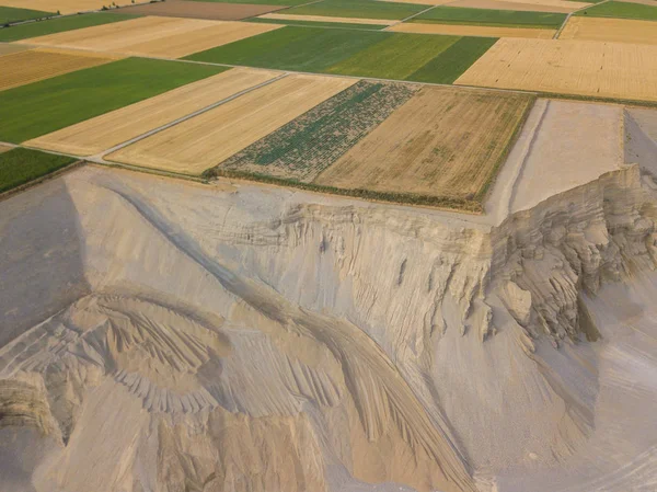 Aerial view of open cast gravel mine in Switzerland. Land grabbing for mining industry. Fields beside gravel quarry.