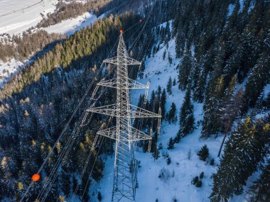 İsviçre 'deki Alp Vadisi' nden geçen elektrik hattının havadan görüntüsü. Kar kışın ağaçları kapladı. Güç iletimi kavramı.