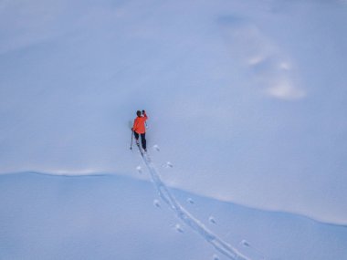Dağcının karla kaplı kırsalda kayak turu yaptığı hava manzarası. Taşra kayağı kavramı.