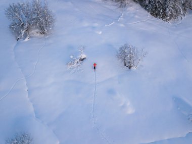 Aerial view of mountaineer hiking upwards with touring ski in snow covered backcountry. Concept of backcountry skiing. clipart