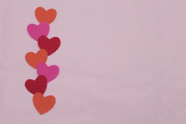 Renkli kalpler pembe arka planda yatar. Boşluğu kopyala.